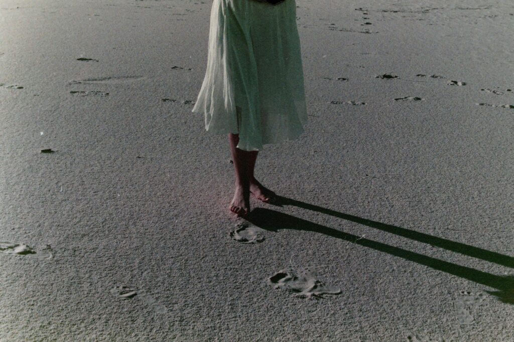 woman in white skirt walking on sand