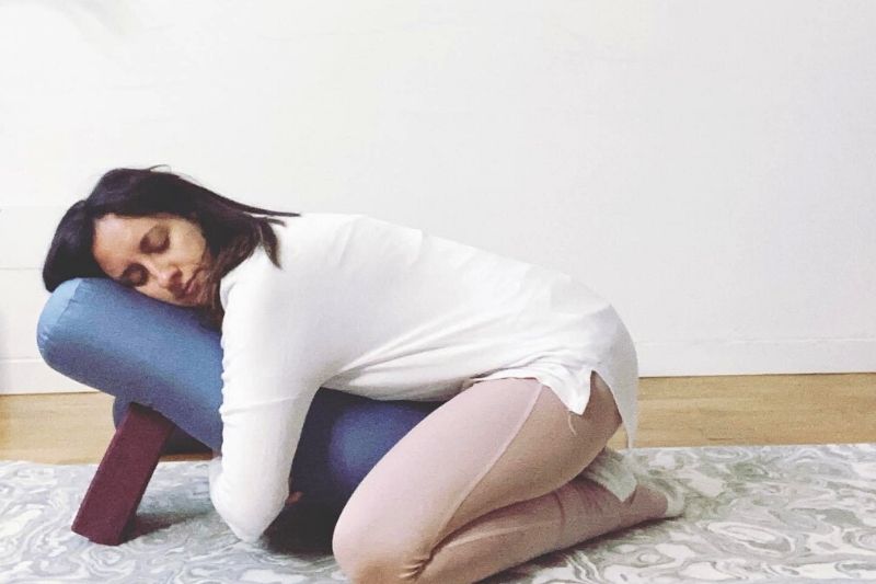 Giorgia Colavolpe pratica una posizione di restorative yoga grazie a dei cuscine che la sostengono e la portano al massimo del rilassamento